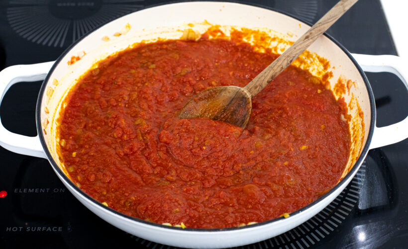Tomato sauce in a skillet with a wooden spoon. 