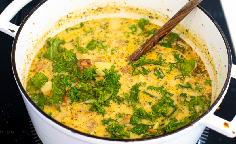 Tuscan soup with kale being added into it. 