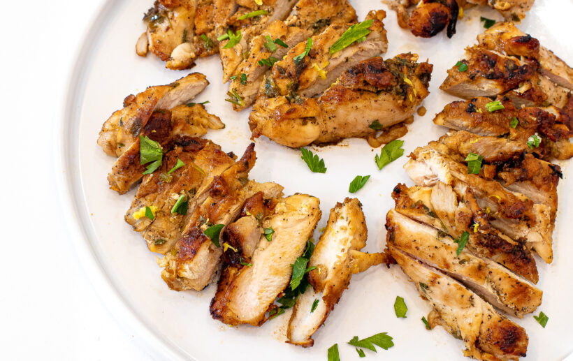 Chicken thighs sliced up on a white plate.