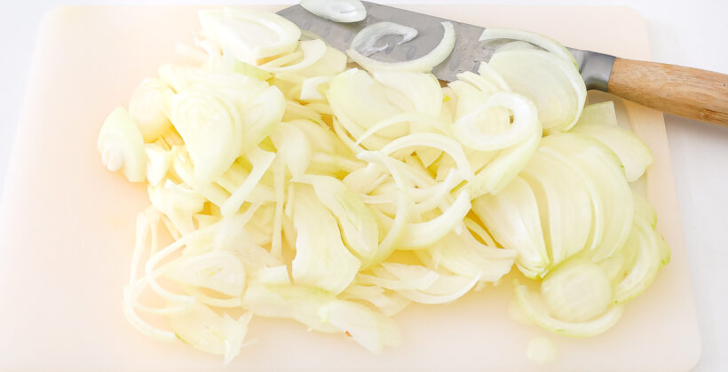 Onions sliced on a cutting board.