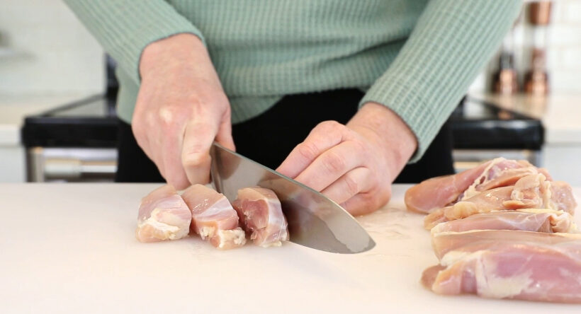 cutting chicken thighs into bite size pieces