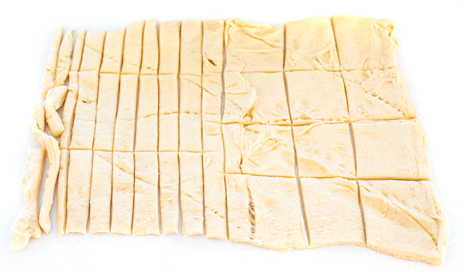Crescent roll dough cut in strips and squares. 