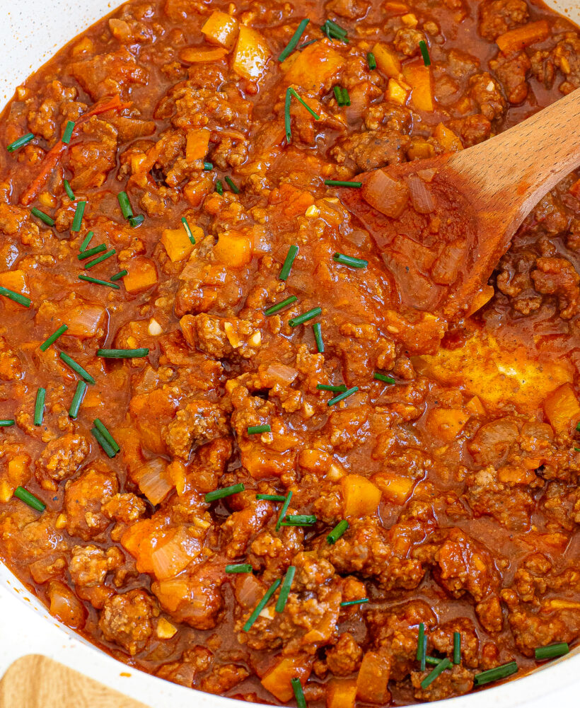 Sloppy joe filling in a skillet with a wooden spoon. 