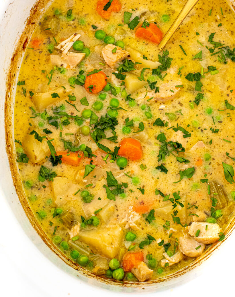 A top down view of slow cooker chicken stew in a white slow cooker liner.