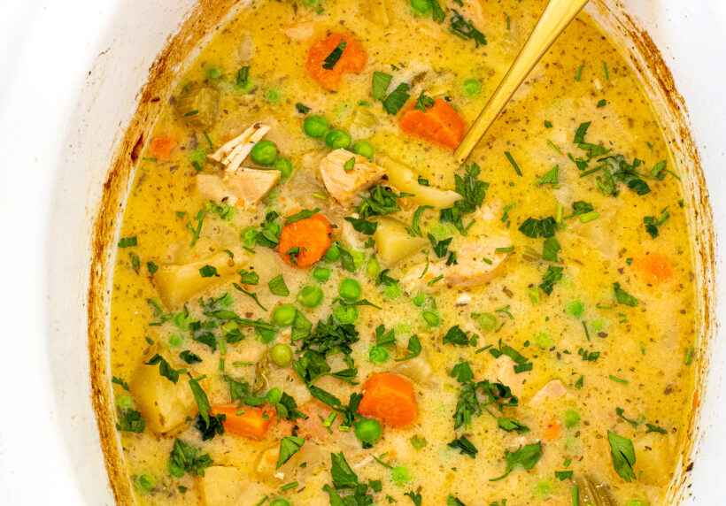 A top down view of slow cooker chicken stew in a white crockpot liner.