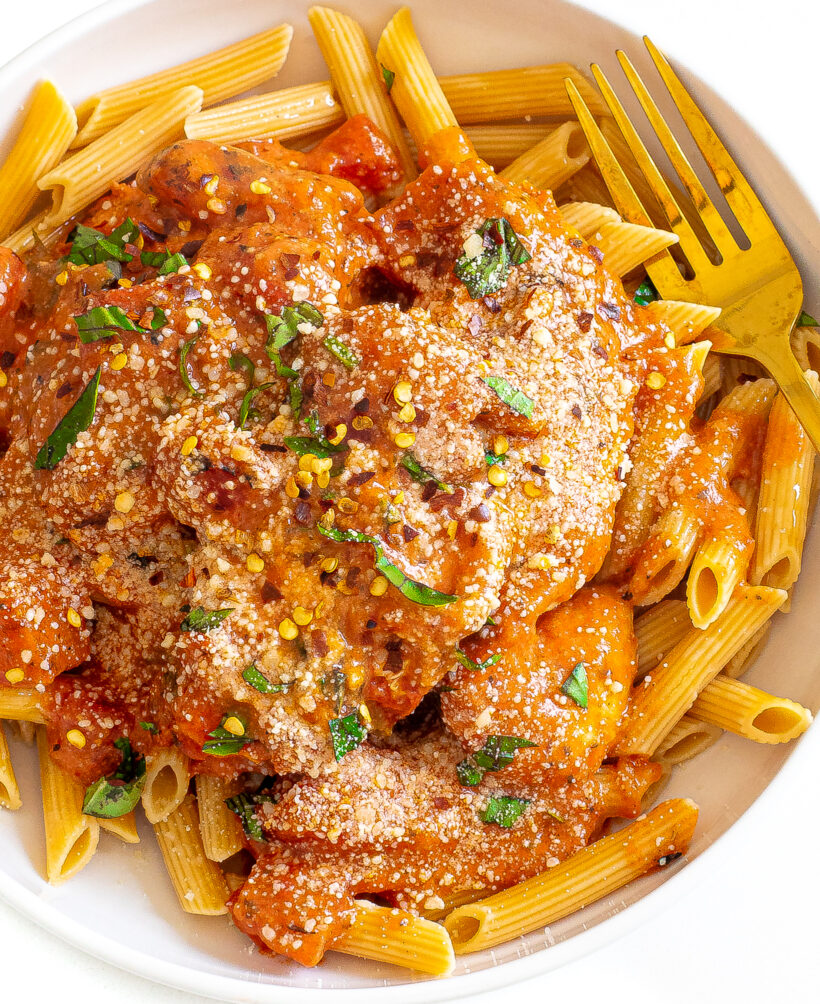 Pasta served with tomato basil chicken topped with basil and red pepper flakes.