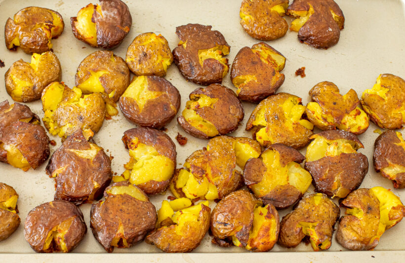 Baked smashed potatoes on a baking sheet.