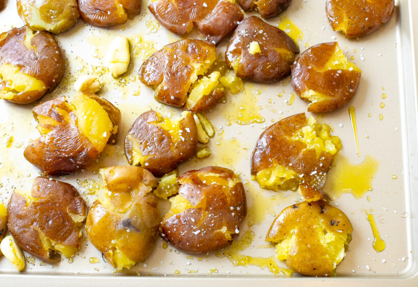 Potatoes smashed on a baking sheet before being baked.