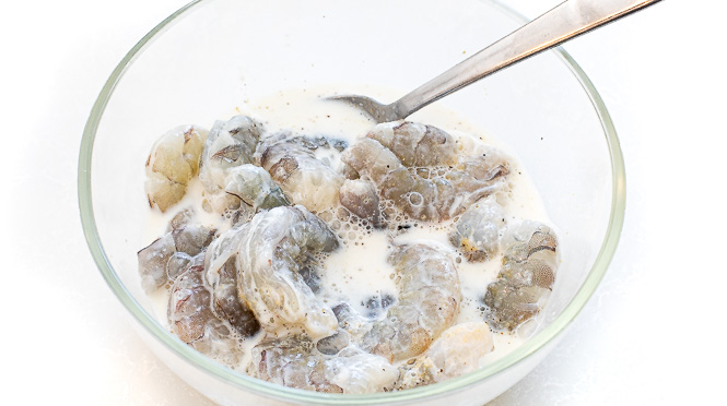 Shrimp in a marinade in a mixing bowl. 