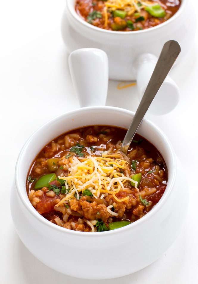 stuffed pepper soup in white bowls topped with shredded cheese and parsley
