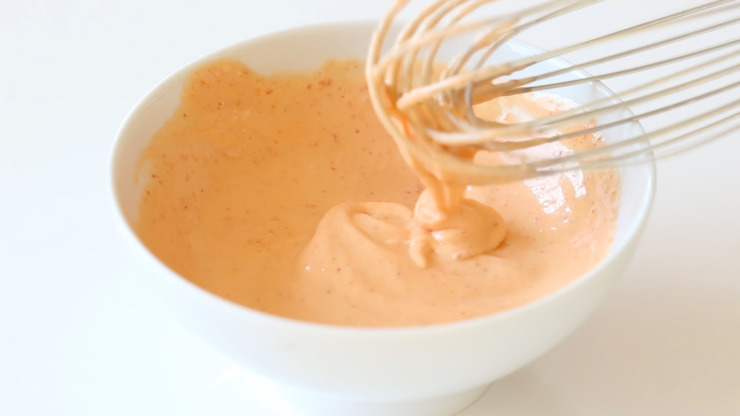 Spicy mayo being whisked together in a small white bowl. 