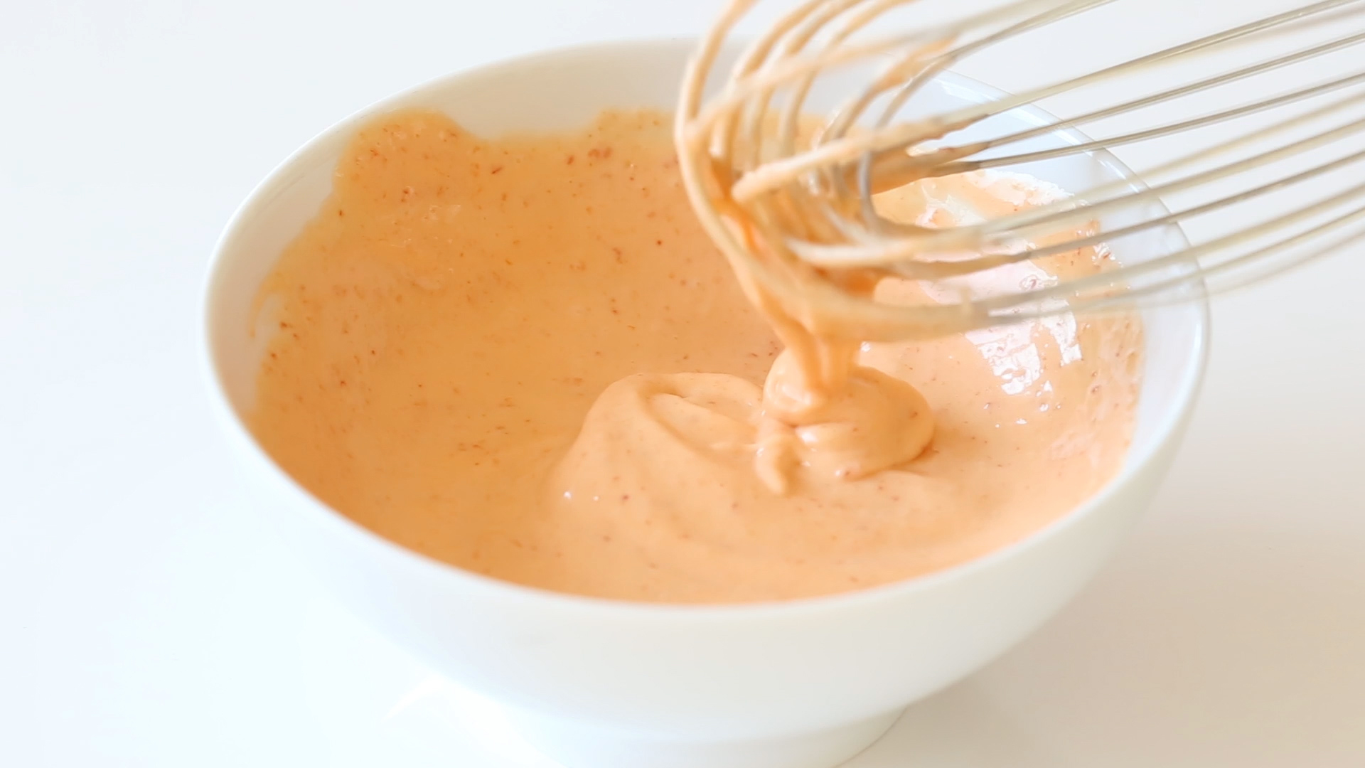 whisking sriracha and mayo in small white bowl for salmon sushi bowls
