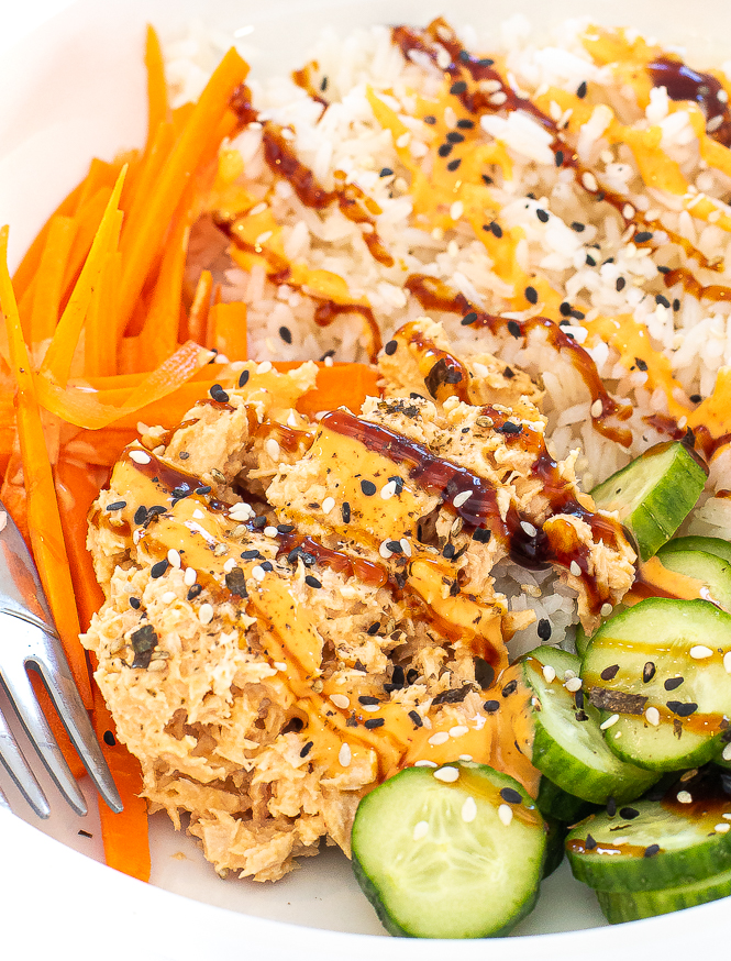 Spicy tuna bowl with rice in a white bowl with a silver fork.