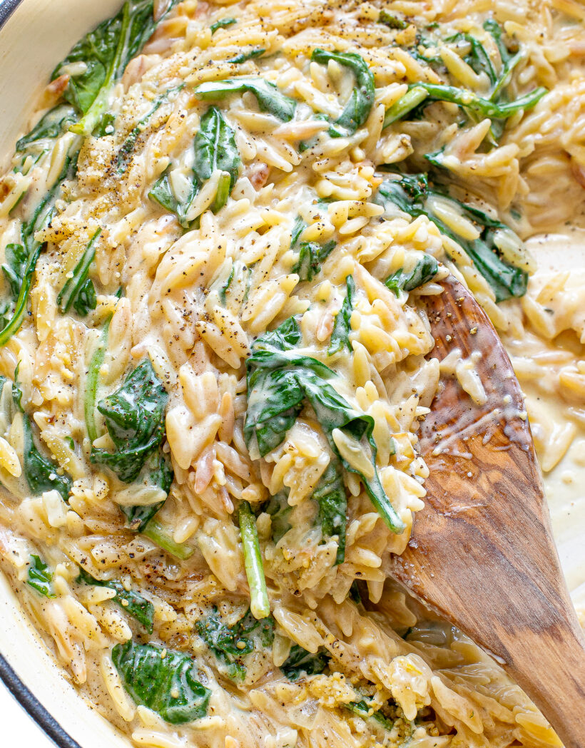 Creamy boursin orzo in a skillet with a wooden spoon.