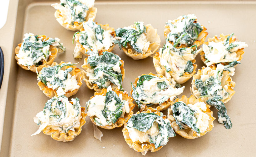 Unbaked spinach phyllo cups on a baking sheet.