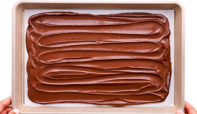 spreading melted chocolate onto baking sheet