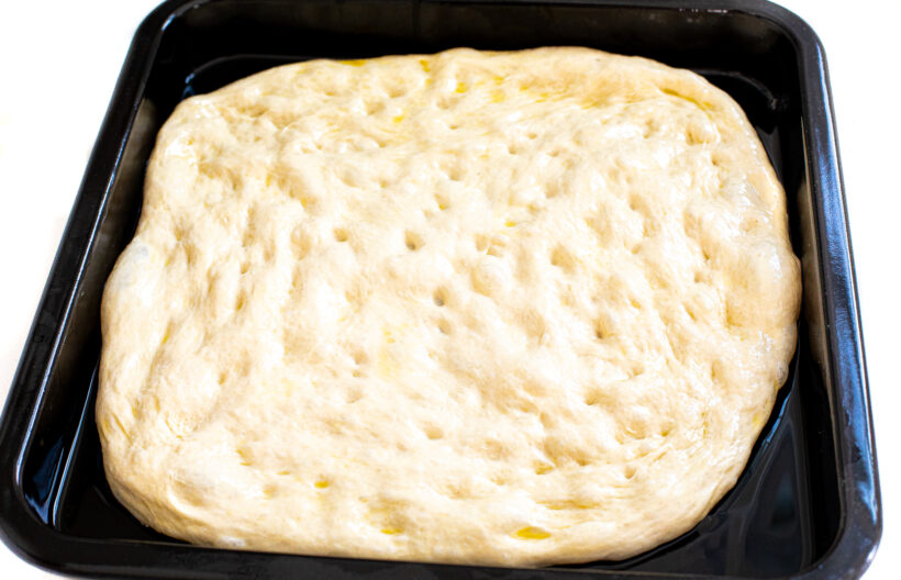 Pizza dough pressed into pizza pan.
