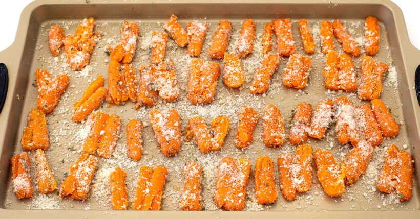 Smashed carrots sprinkled with parmesan on a baking sheet.