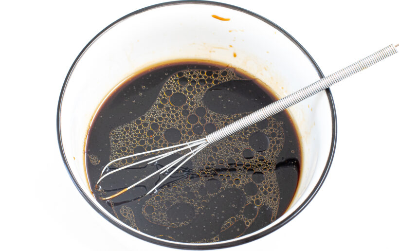 Sauce ingredients in a glass bowl with a whisk.