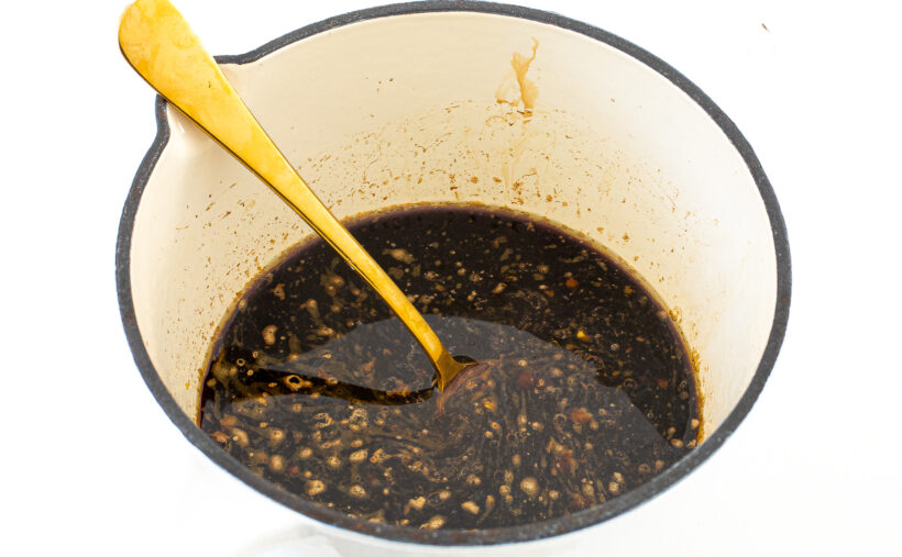Stir Fry Sauce in a white saucepan stirred with a gold spoon.