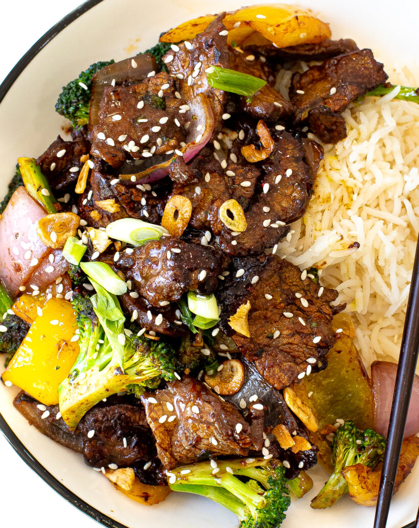 Close up view of beef stir fry in a bowl with rice.