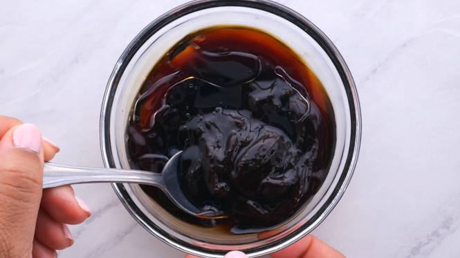 Asian sauce being mixed together with a silver spoon in a small bowl. 