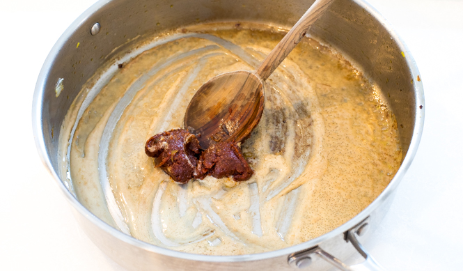 Adding curry paste to reduced coconut milk in large skillet