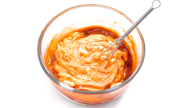 Mixing the sriracha, mayonnaise, and sesame oil in a small bowl with a whisk.