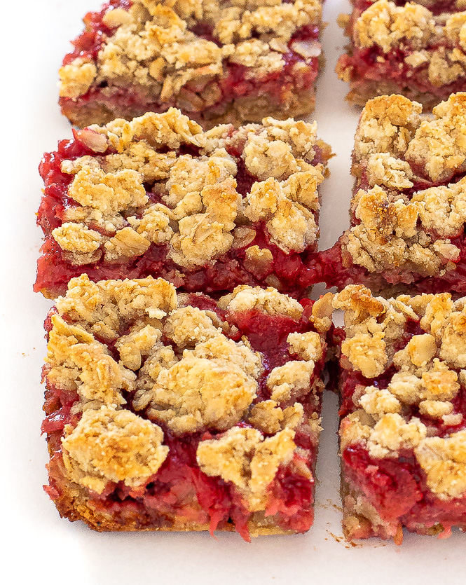 Up close shot of strawberry oatmeal bars lined up on a white plate.
