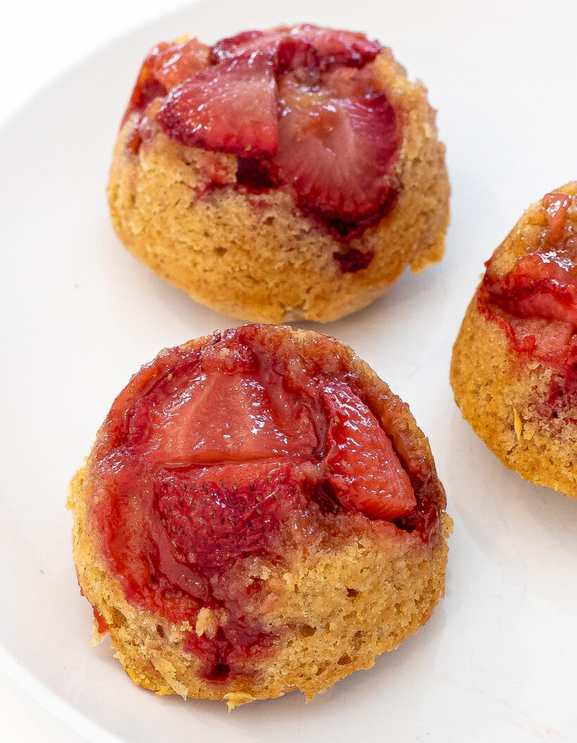 Mini strawberry upside down cakes lined up on a white plate. 