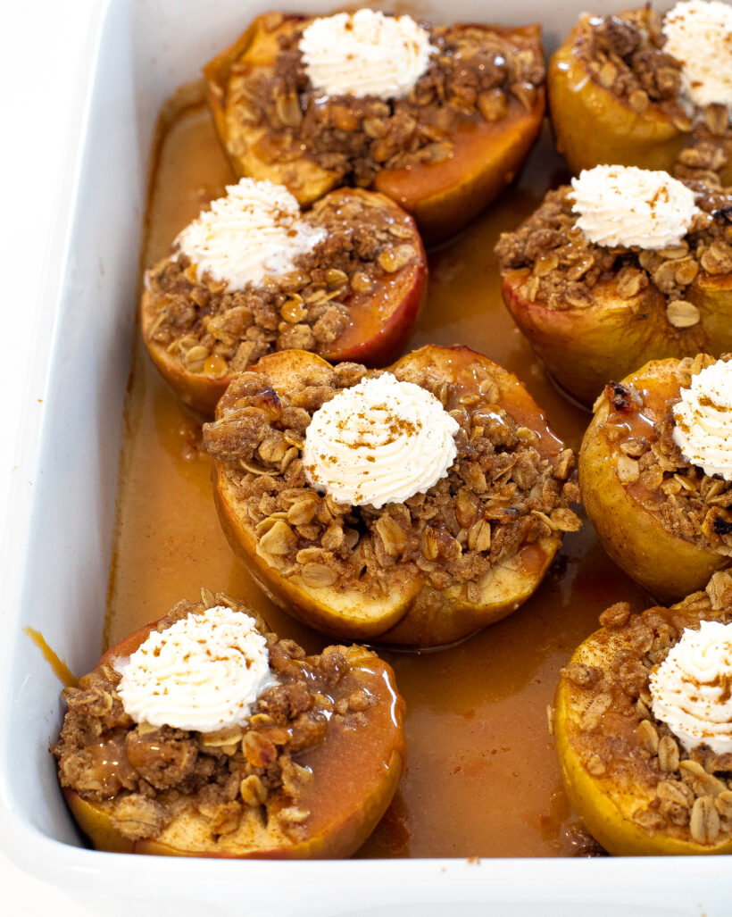 Stuffed baked apple crisp in a making dish topped with whipped cream and caramel.