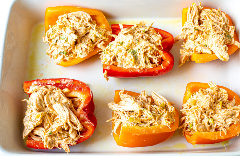 Stuffed peppers in a white baking dish.