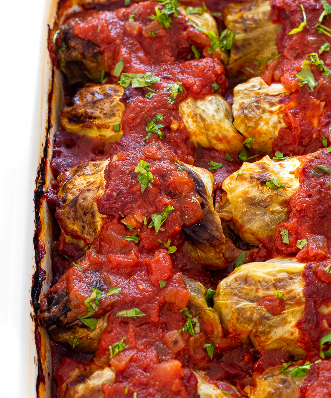 Close up shot of cabbage rolls in a white baking dish after being baked. 