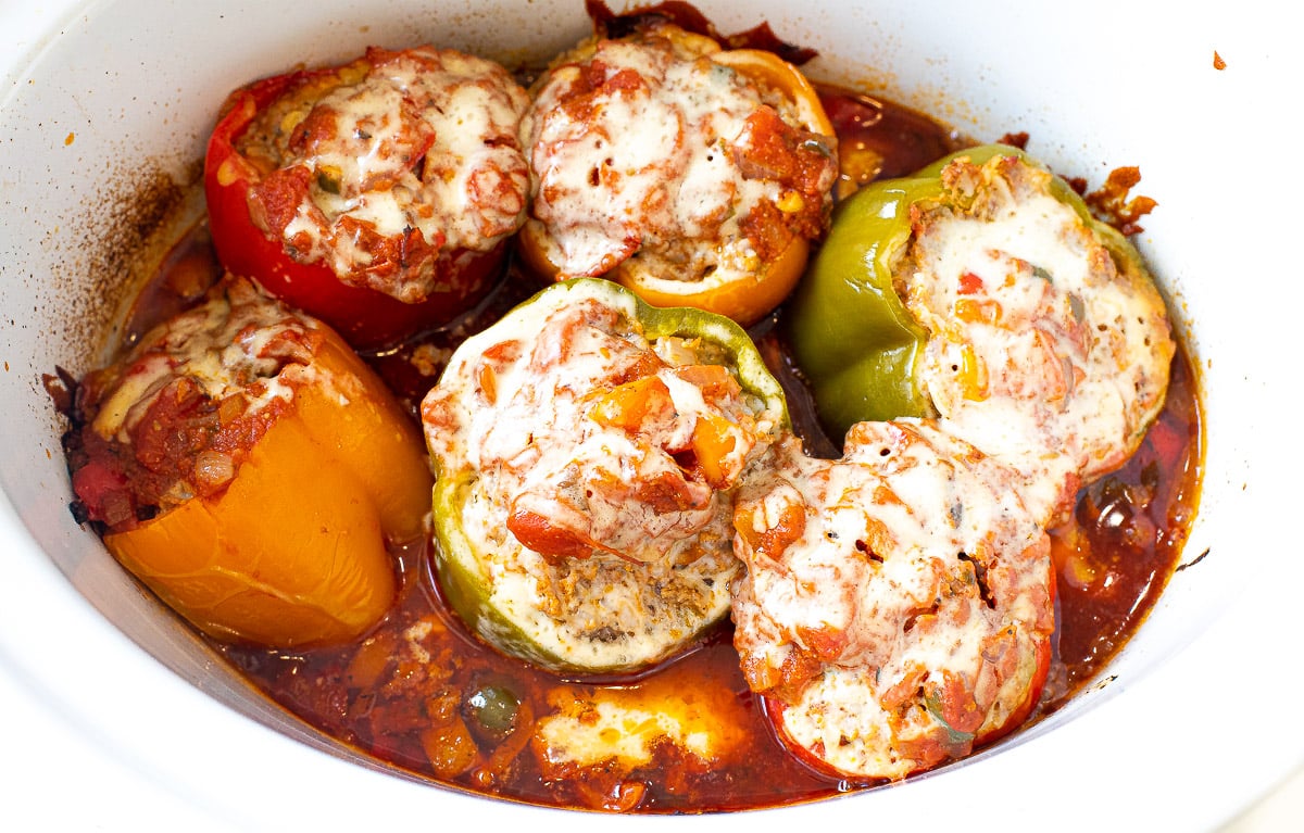 cooked stuffed peppers in slow cooker topped with melty cheese