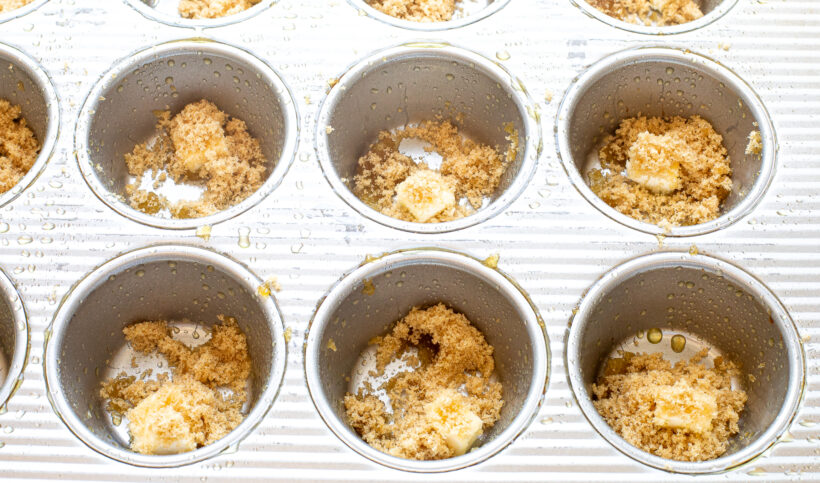 Butter and brown sugar in the muffin wells of a muffin tin.