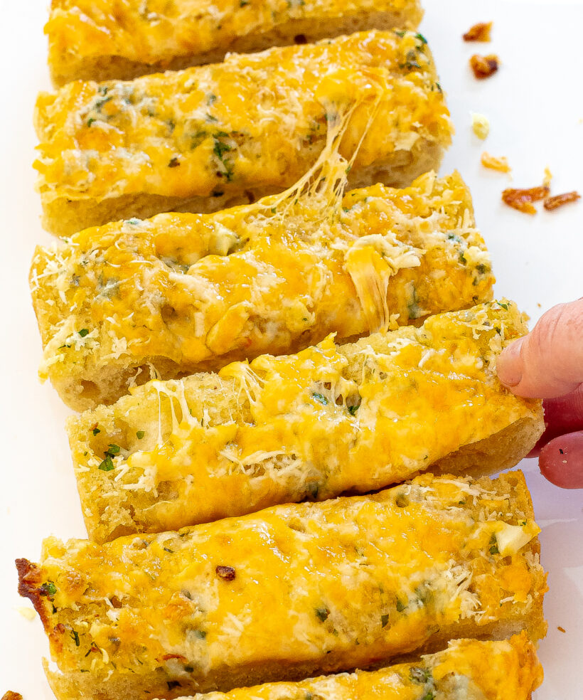 Hand taking a piece of garlic bread. 