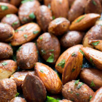 close up shot of spicy almonds with cilantro flakes