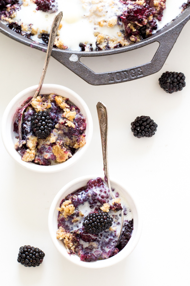 Old Fashioned Berry Crisp | chefsavvy.com Old Fashioned Berry Crisp in 2 white bowls with spoons next to cast iron skillet.