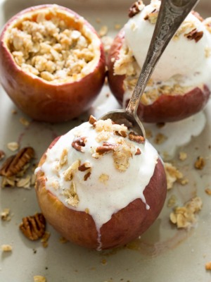 This Stuffed Baked Apple Crisp recipe on a baking sheet with vanilla ice cream, chopped pecans, and a spoon | chefsavvy.com #recipe #dessert #baked #apple