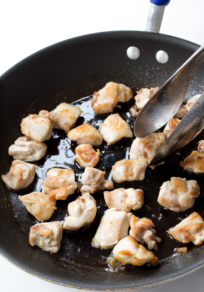 Teriyaki chicken bites cooking in black skillet with olive oil