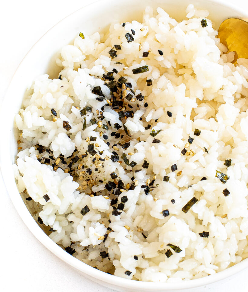 Sushi rice served in a white bowl with furikake seasoning on top.