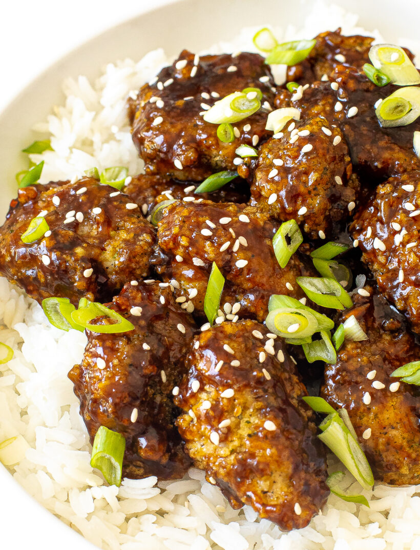 close up shot of asian chicken bites in bowl with white rice
