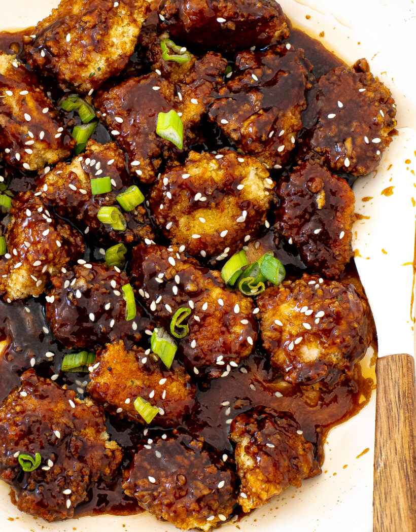 overheat shot of saucey honey sriracha chicken in large skillet with green onions and sesame seeds