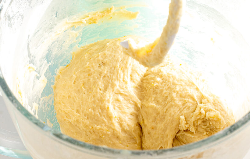 Brioche dough in a stand mixer bowl with a dough hook.