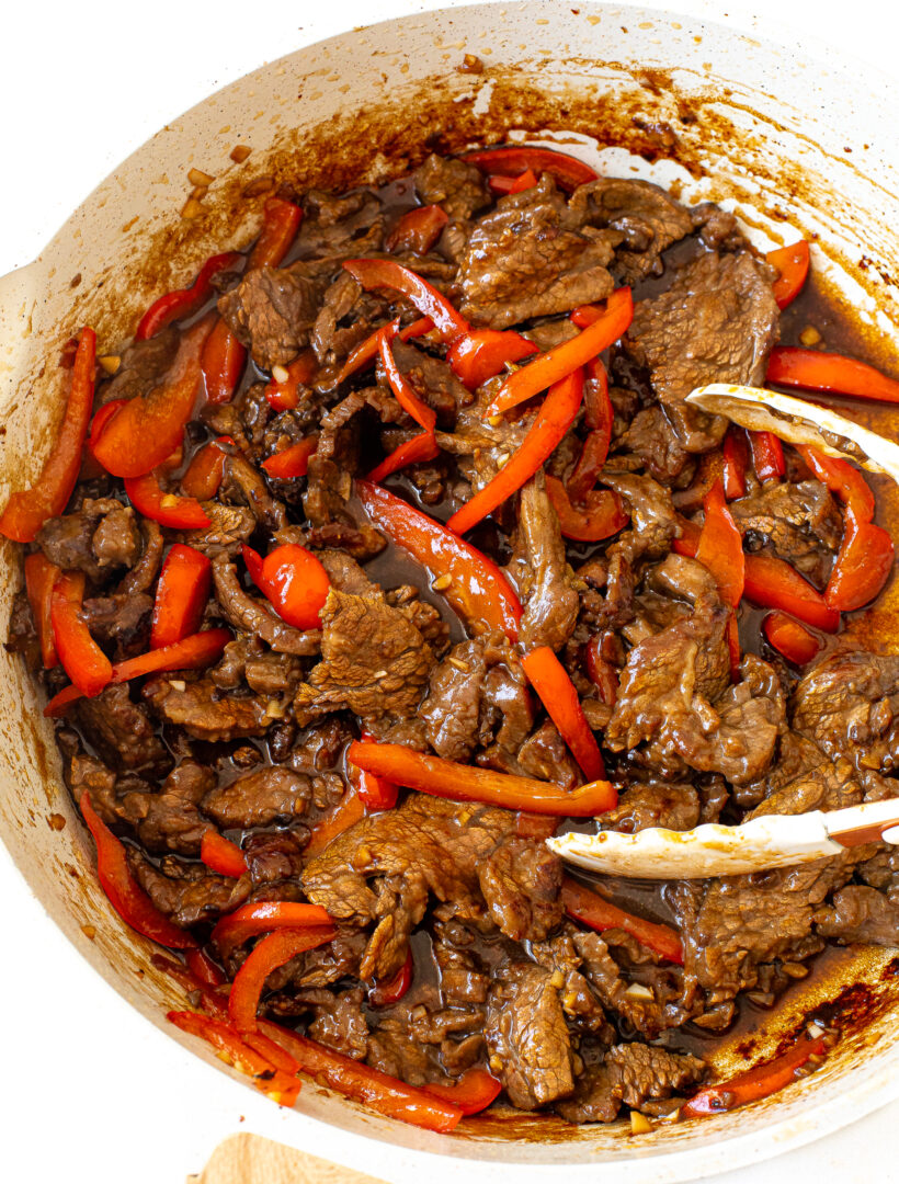 Authentic Szechuan Beef | chefsavvy.com overhead shot of saucey Szechuan beef with bell peppers, garlic and ginger