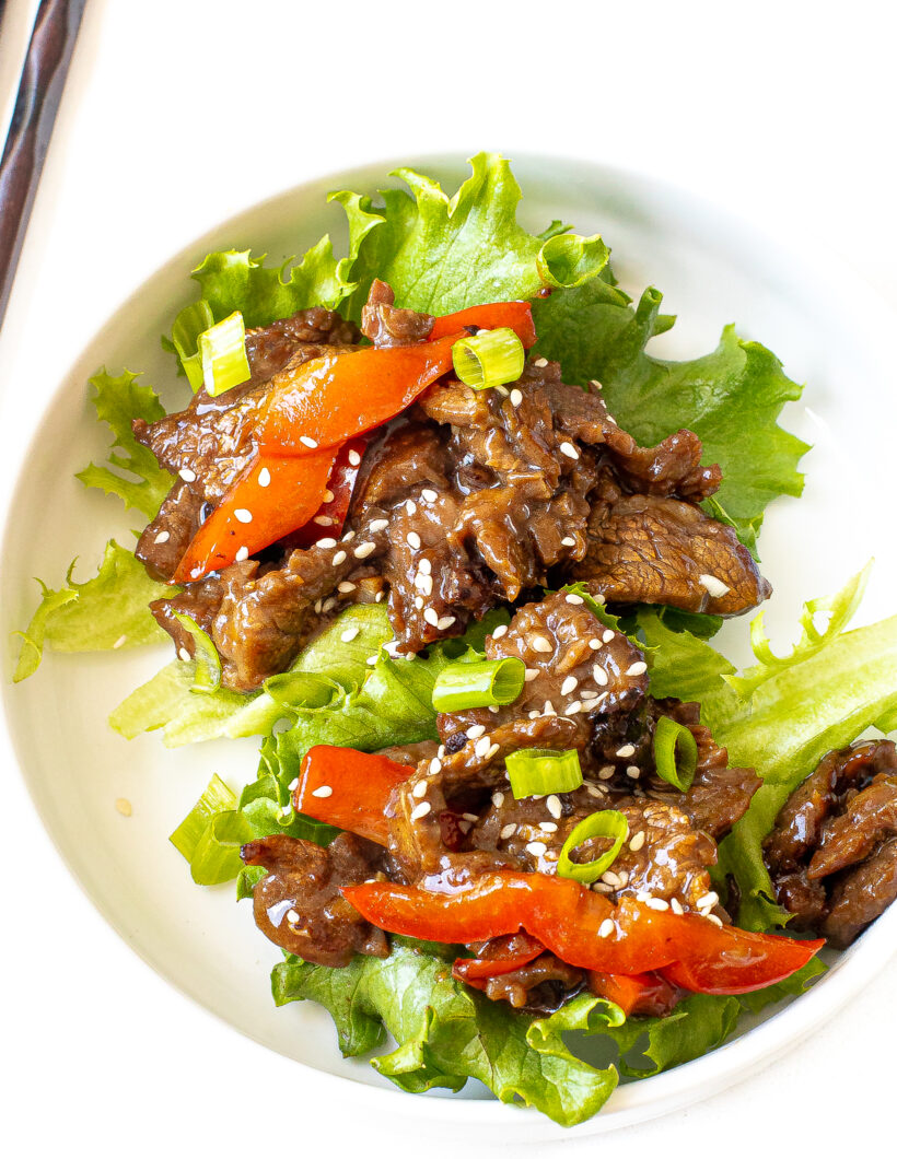 overhead shot of Szechuan beef stir fry in lettuce cups on white plate