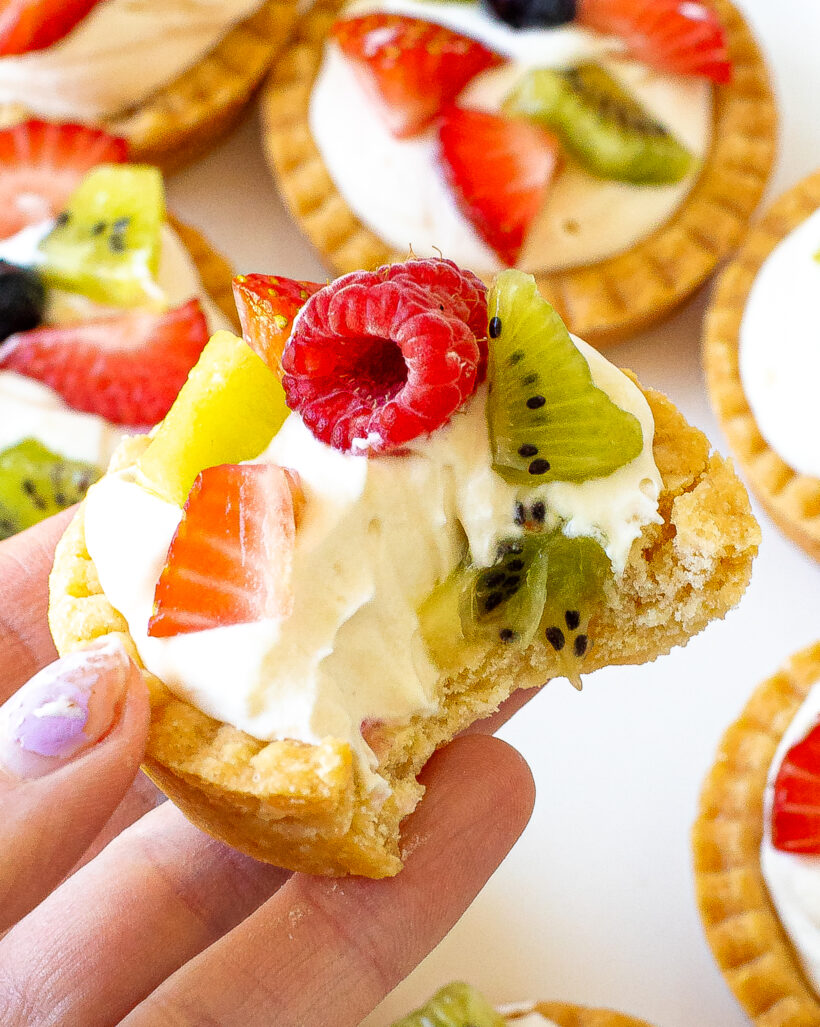 Mini fruit tart with a bite taken out of it.