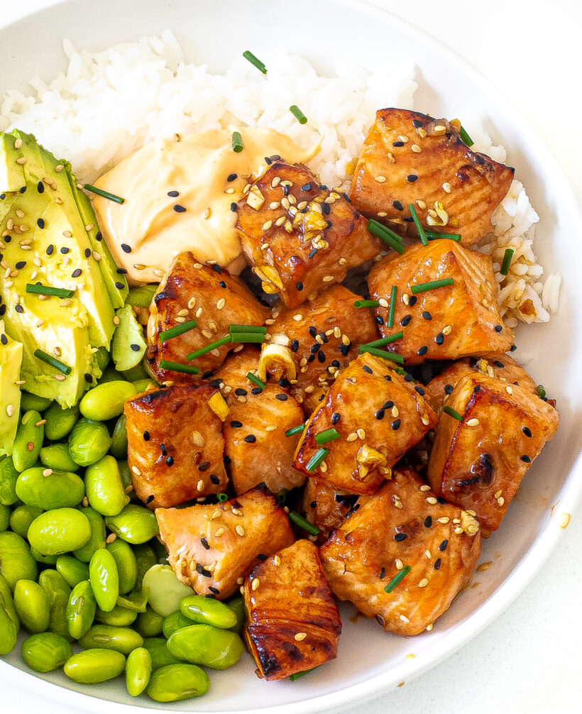 Salmon bites served in a bowl with rice, edamame, avocado and mayo. 