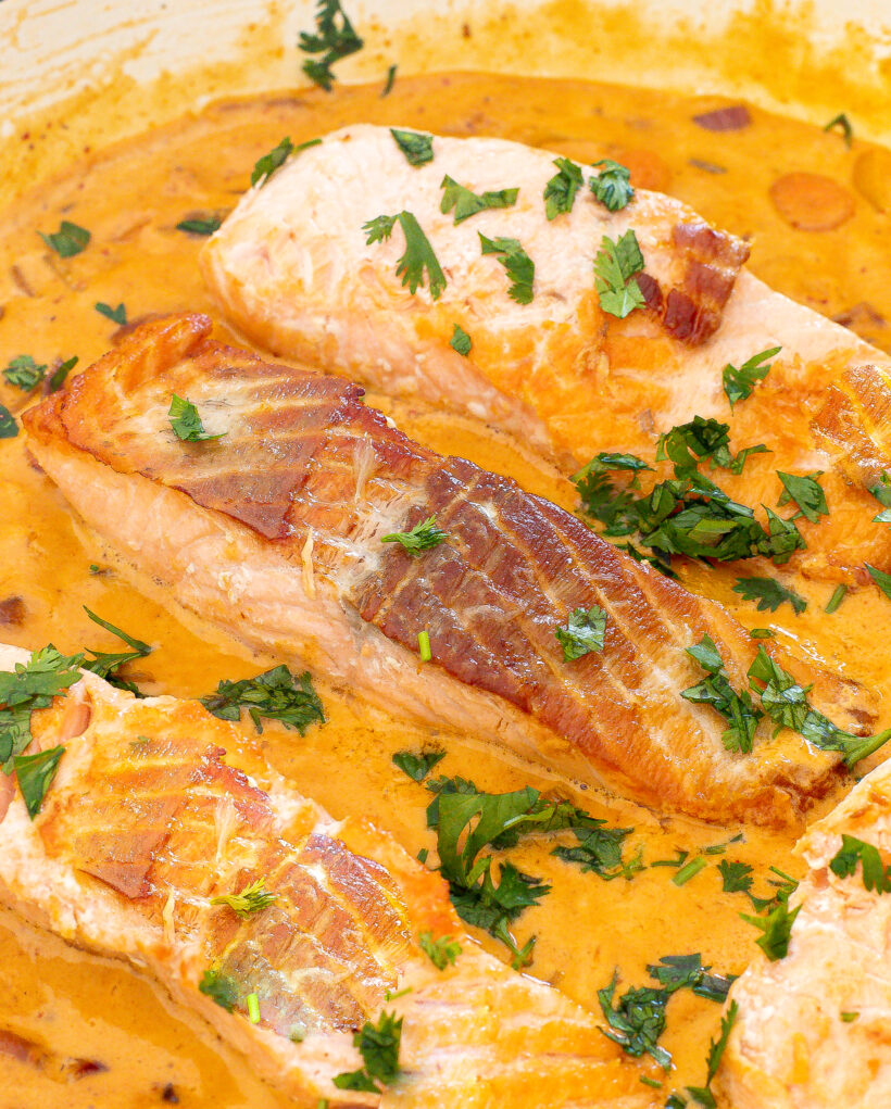 Salmon in a curry sauce in a sauté pan.
