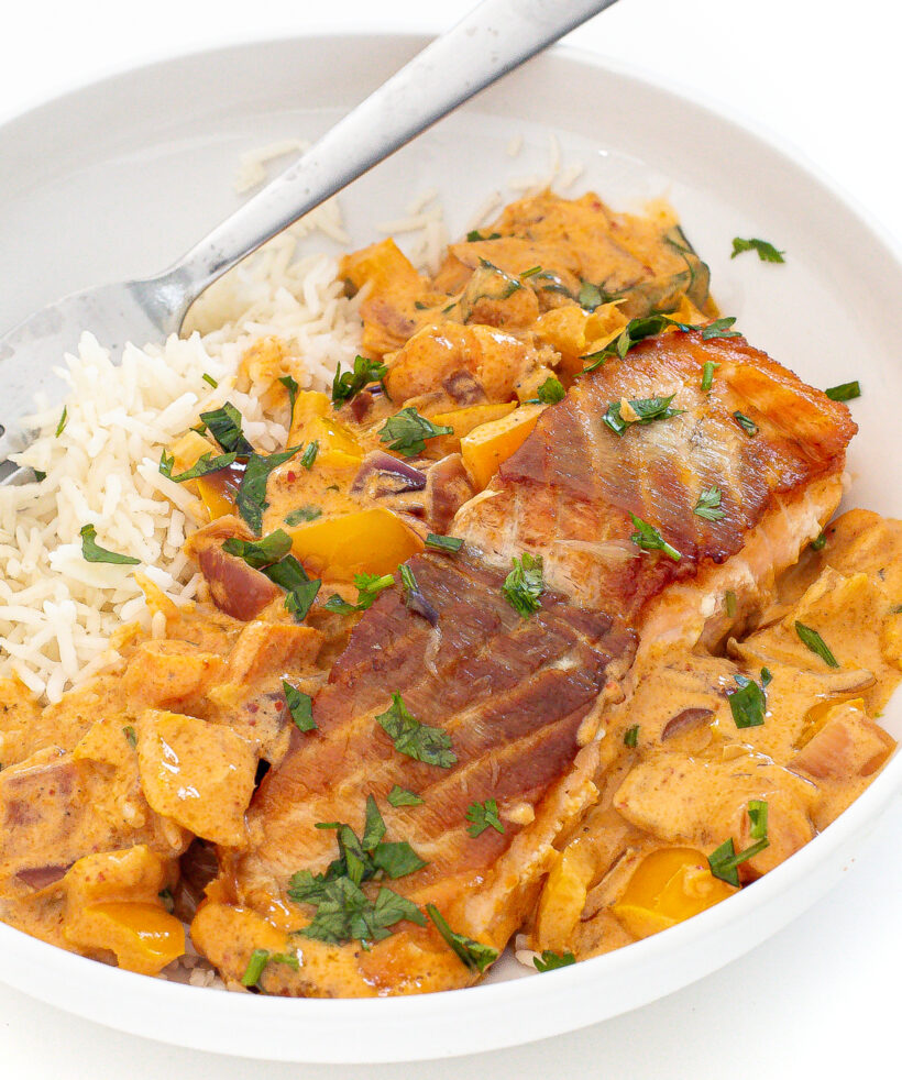 Salmon curry over rice in a white bowl.